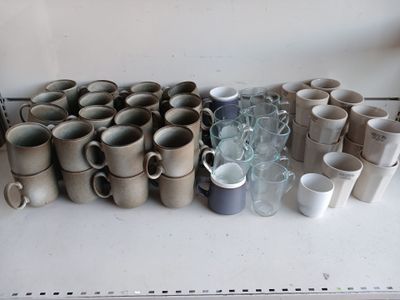 many cups and mugs sitting on a shelf in a room