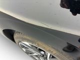 a man standing next to a car that has a denting on it