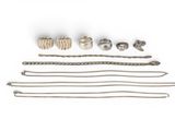 an assortment of silver jewelry on a white surface with a white background