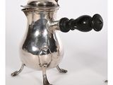 une cafetière ancienne en argent avec une poignée en bois sur un support