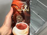 a person holding a bag of coffee in front of an open refrigerator