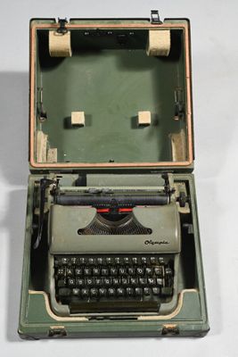 une vieille machine à écrire posée sur une table, son capot ouvert