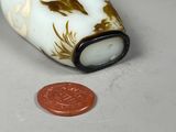 a small bottle with a gold design on it next to a penny