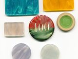 plusieurs savons de différentes couleurs et des pains de savon posés sur une surface blanche