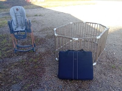 two chairs and a suitcase sitting in the dirt