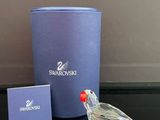 un petit oiseau en verre posé sur une table, à côté d'une boîte bleue