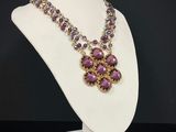 a white mannequin with purple beads and a necklace on it