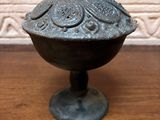 a small metal bowl with a lid on a wooden table