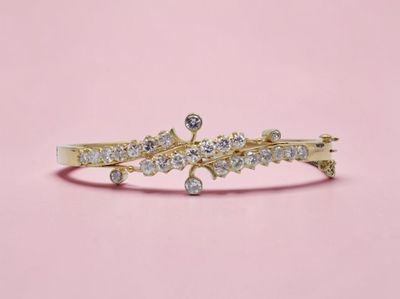 un gros plan d'une bague en or sertie de diamants sur fond rose