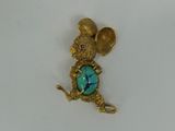 a close up of a gold mouse brooch with a turquoise stone