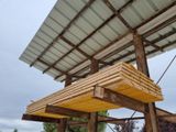 a wooden bench under a metal roof in a field