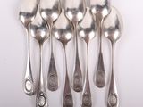 six silver spoons are lined up in a row on a white surface