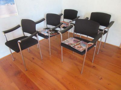 four black chairs in a room with a magazine on the table