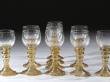 six verres à vin dorés sont alignés sur une surface blanche