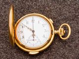 une montre de poche en or posée sur un tissu marron