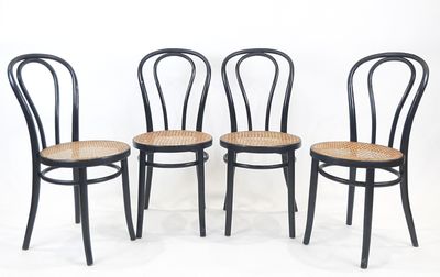 quatre chaises noires avec des assises en osier, sur fond blanc