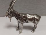 une figurine de chèvre en argent posée sur une surface blanche