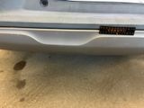 the rear end of a silver car with a sticker on it ' s bumper