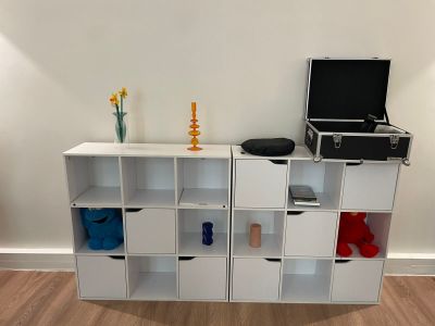une bibliothèque blanche sur laquelle sont posés de nombreux objets divers
