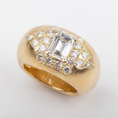 a close up of a gold ring with an emerald center surrounded by diamonds