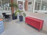 a red cabinet in the middle of a room with a potted plant