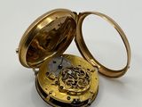 une vieille montre de poche posée sur une surface blanche