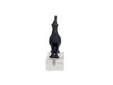 une statue noire représentant un chat assis sur une surface blanche