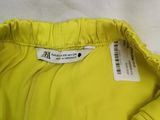 someone is holding a yellow jacket that has a tag on it