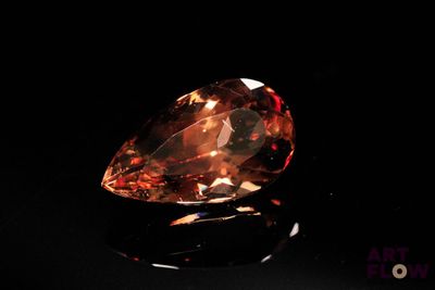 un gros plan sur un gros diamant orange posé sur une surface noire