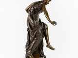 a bronze statue of a woman sitting on a rock