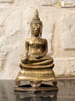 statue d'un Bouddha assis sur une table devant un mur de pierre