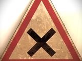 un panneau triangulaire rouge et blanc sur lequel figure un X noir