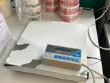 une photo d'une balance posée sur un bureau, recouverte de nombreux morceaux de ruban adhésif