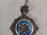 silver and blue pendant on a chain on a white surface