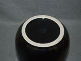 a black vase with a white rim sitting on a table