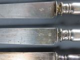 six silverplated knives are lined up next to each other on a table