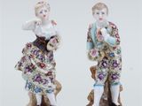 pair of porcelain figurines of a man and a woman on a rock