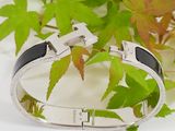a silver bracelet with a cross on it next to some leaves