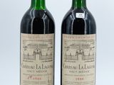 two bottles of red wine sitting next to each other on a white surface