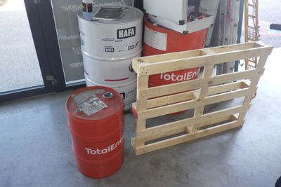 un fût rouge posé à côté d'une pile de fûts dans un garage