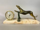 a statue of a dog that is jumping over a clock