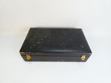 une petite valise noire posée sur une surface blanche