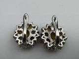 a pair of silver earrings with yellow stones on them