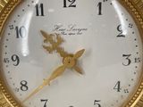 a gold clock with a white face on a white surface