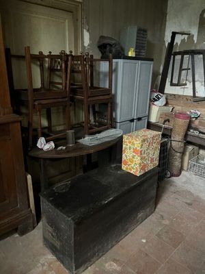 une malle noire posée au milieu d'une pièce remplie de meubles