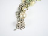 a close up of a necklace with pearls and flowers on it