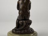 bronze sculpture of a boy sitting on a rock