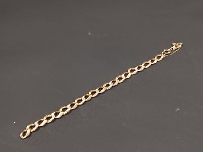gros plan d'un bracelet en chaîne en or sur une surface noire