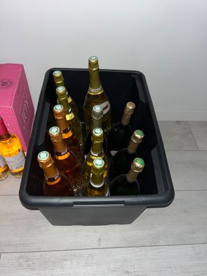 bottles of beer in a black container next to a pink box on the floor