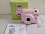 a pink camera sitting on top of a table next to a box